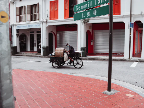 A delivery tricycle loaded with boxes passing old shophouses on Gemmill Lane, Singapore