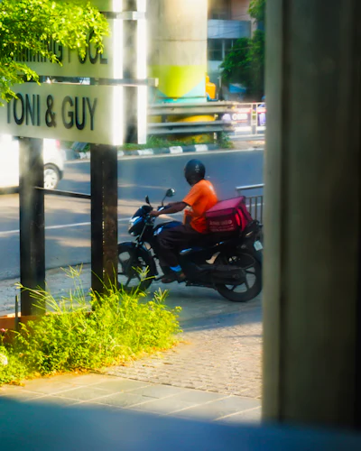 Delivery rider with a red box turning a street corner