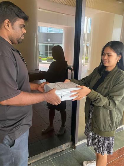 A courier handing a parcel to a customer at her doorway